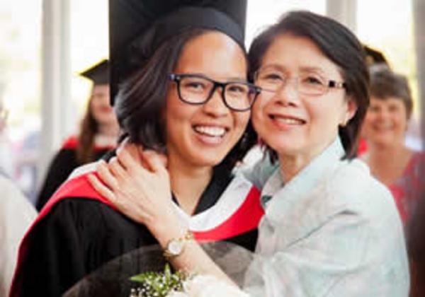 A woman hugging a graduate in cap and gown. 