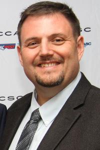 Smiling man in a dark suit.
