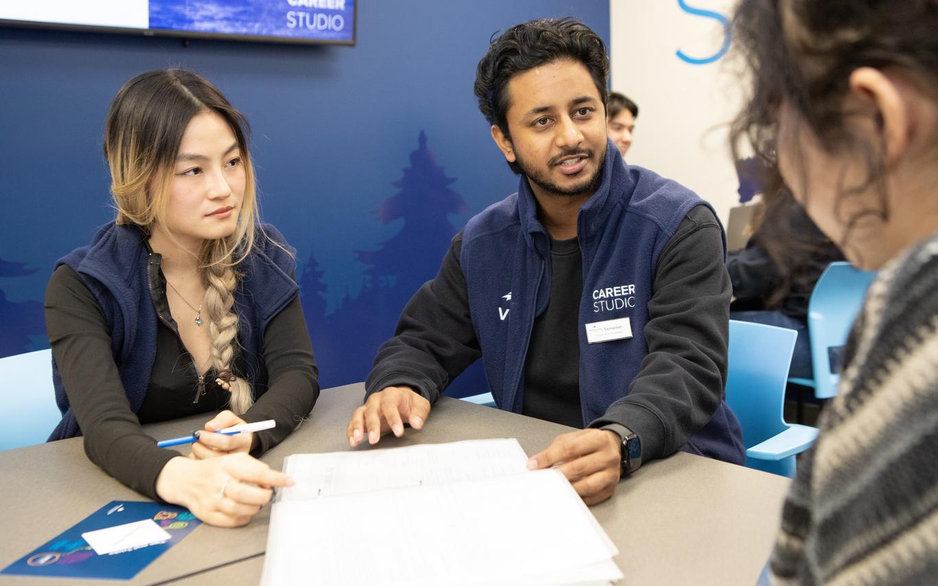 Female and male Career Studio team members talking to a student